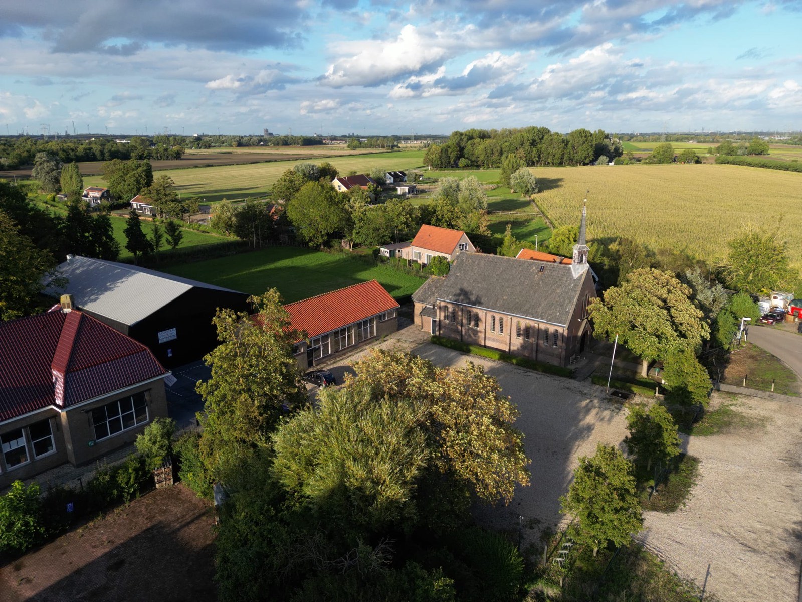 Luchtfoto van de kerk van Tinte tussen de akkers en de dorpsbebouwing
